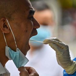 Un trabajador de la salud toma una muestra de hisopo de un hombre para detectar el coronavirus Covid-19 en el distrito de Huangpu de Shanghái. Hector RETAMAL / AFP. | Foto:AFP