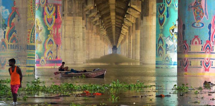 Los hombres descansan en un bote en el río Ganges desbordado bajo el puente Shastri en Allahabad, cuando los niveles de agua de los ríos Ganges y Yamuna aumentaron tras las lluvias monzónicas. SANJAY KANOJIA / AFP.