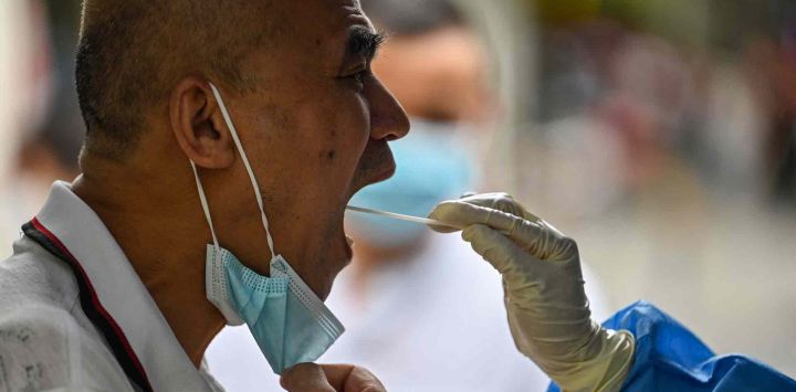Un trabajador de la salud toma una muestra de hisopo de un hombre para detectar el coronavirus Covid-19 en el distrito de Huangpu de Shanghái. Hector RETAMAL / AFP.