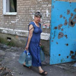 Una mujer lleva botellas de agua mientras pasa frente a un edificio dañado en la ciudad de Avdiivka, región de Donetsk, en medio de la invasión militar rusa de Ucrania. Anatolii Stepanov / AFP. | Foto:AFP
