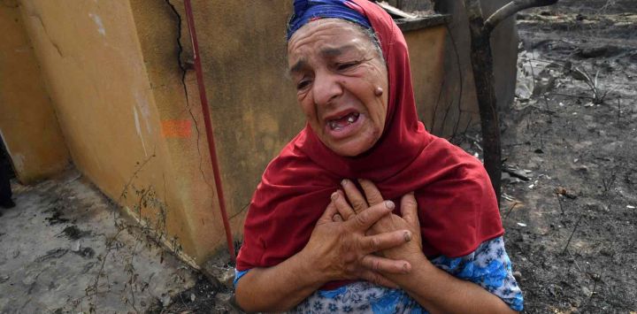 Una anciana argelina reacciona frente a las ruinas de su casa, destruida por un incendio forestal en la ciudad de el-Kala. AFP.