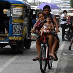 Una familia monta una bicicleta a lo largo de una calle en Manila. Jam Sta Rosa / AFP. | Foto:AFP
