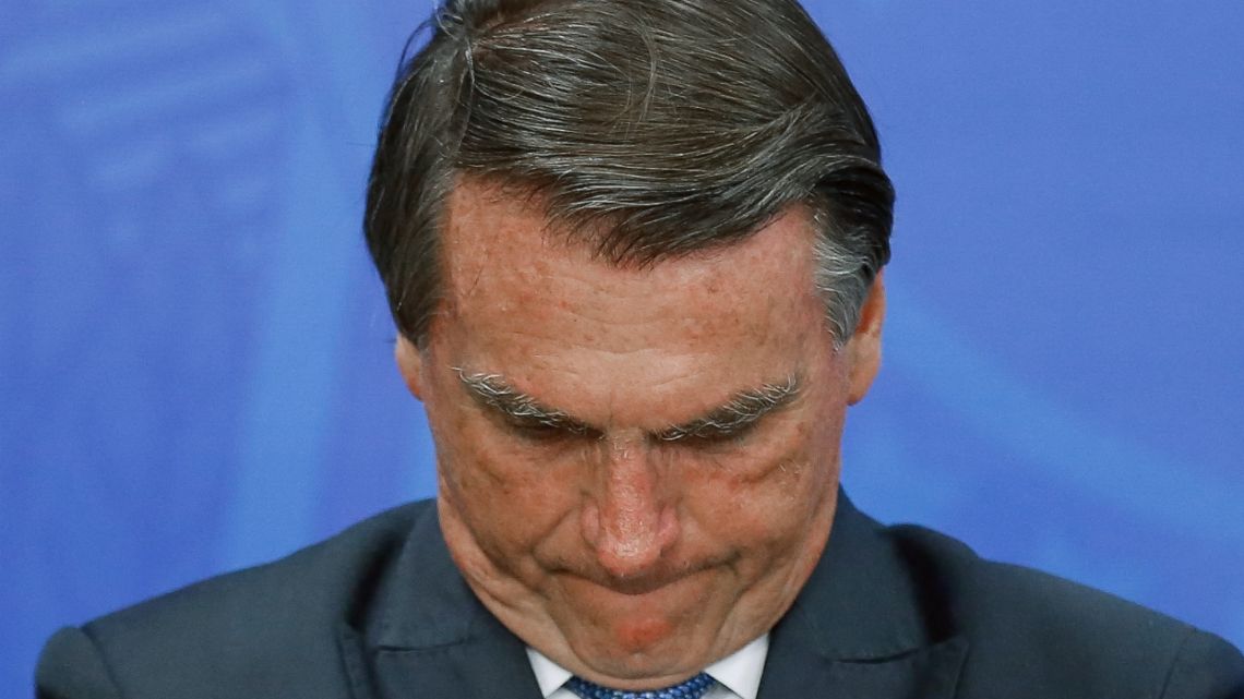 (FILES) In this file photo taken on July 6, 2022, Brazilian President Jair Bolsonaro gestures during a tribute to the Brazilian athletes who won the second place in the general medal table of the Normandy 2022 Gymnasiade in Brasilia. Brazilian President Jair Bolsonaro got into an altercation on Thursday August 18, 2022 with a social media personality who questioned and insulted him, grabbing the man by the shirt and arm after he called him a "bum."
