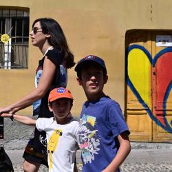 Una familia de turistas pasando frente a una casa con la escultura de un sol en la ventana y un corazón dibujado en la puerta en Naviglio, al sur de Milán. MIGUEL MEDINA / AFP. | Foto:AFP