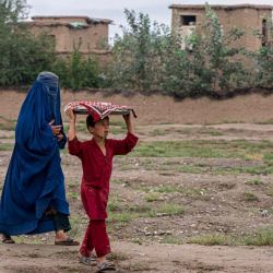 Una mujer afgana vestida con burka camina con un niño en el distrito de Bagram en la provincia de Parwan. Wakil KOHSAR / AFP. | Foto:AFP