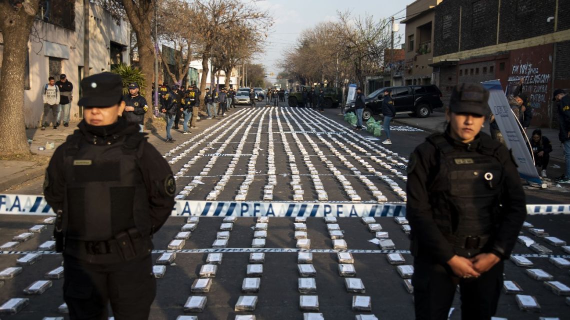 Police stand guard over seized packages of cocaine displayed to the press in Rosario, Santa Fe Province, Argentina on August 26, 2022. Federal Police officers seized more than 1,600 kilos of cocaine, valued at some US$60 million, which were about to leave through the waterway to Dubai, authorities said.