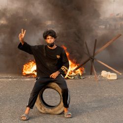Un partidario del clérigo chiíta iraquí Moqtada Sadr posa para una foto en una carretera bloqueada con neumáticos en llamas durante una manifestación en la ciudad de Basora, en el sur de Irak. | Foto:Hussein Faleh / AFP
