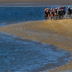 Los jinetes corren por una playa durante las carreras anuales de caballos en la playa de Sanlúcar de Barrameda, cerca de Cádiz. | Foto:CRISTINA QUICLER / AFP