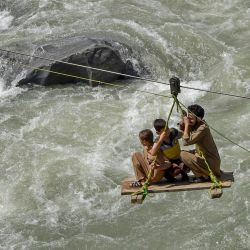 Los residentes locales utilizan un servicio de cuna temporal para cruzar el río Swat después de las fuertes lluvias en la ciudad de Bahrain del valle de Swat en la provincia de Khyber Pakhtunkhwa, Pakistán. | Foto:ABDUL MAJEED / AFP