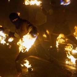 Imagen de jóvenes portando máscaras y guantes mientras lanzan bolas de fuego durante la celebración del centenario de la tradición de "Las Bolas de Fuego", en el municipio de Nejapa, El Salvador. | Foto:Xinhua/Alexander Peña