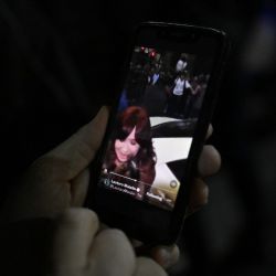 A person watches a video on a mobile phone showing a man pointing at Vice-President Cristina Fernández de Kirchner outside her residence in Buenos Aires on September 1, 2022. A man was arrested Thursday for pointing a gun at then forme president as she arrived at her home, said Security Minister Aníbal Fernández. 