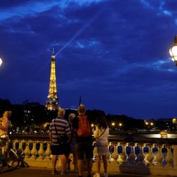 Un grupo de turistas se reúnen en el Puente Alejandro III en París, mientras observan un espectáculo de luces en la Torre Eiffel. | Foto:Ludovic Marin / AFP