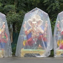 Un vendedor espera a los clientes sentado frente a los ídolos del dios hindú con cabeza de elefante Ganesha expuestos para su venta a lo largo de una calle antes del festival Ganesh Chaturthi en las afueras de Hyderabad, India. | Foto:NOAH SEELAM / AFP
