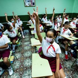Niños levantan las manos en sus aulas en su primer día de clase en La Habana, Cuba. | Foto:YAMIL LAGE / AFP