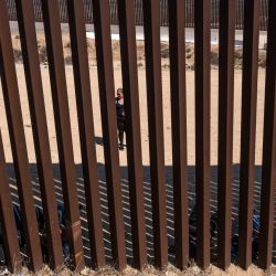 Miembros de un grupo de más de 50 solicitantes de asilo, principalmente de América del Sur, esperan a que las autoridades estadounidenses los procesen después de cruzar la valla fronteriza entre Estados Unidos y México, visto desde Tijuana, estado de Baja California, México. | Foto:Guillermo Arias / AFP
