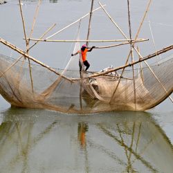Un pescador sobre una red de pesca en las aguas del río Yamuna en Nueva Delhi, India. | Foto:Sajjad Hussain / AFP