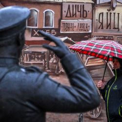 Una mujer con un paraguas pasa por delante de la composición escultórica "Feria" en Serpukhov, a unos 95 kilómetros de Moscú, Rusia. | Foto:Yuri Kadobnov / AFP