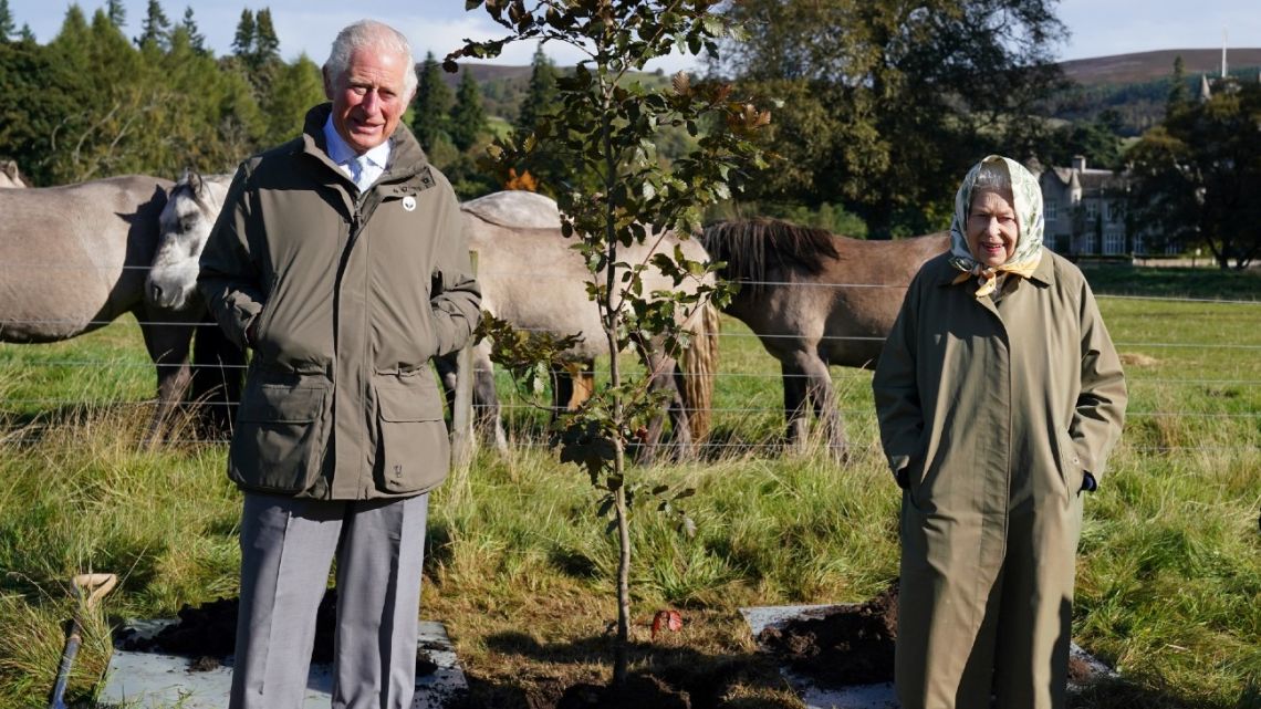 In this file photo taken on October 01, 2021 Britain's Queen Elizabeth II and Britain's Prince Charles, Prince of Wales pose alongside the tree which they planted to mark the start of the official planting season for the Queen's Green Canopy (QGC) at the Balmoral Cricket Pavilion, Balmoral Estate in Scotland. 