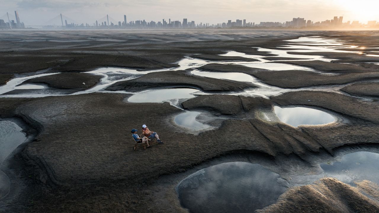 Esta foto muestra a personas sentadas en una sección de un lecho de río reseco a lo largo del río Yangtze en Wuhan, en la provincia central china de Hubei. | Foto:AFP