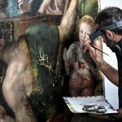 Un artista restaurador trabaja en un cuadro en las obras de restauración de las pinturas de la catedral de Notre-Dame de París, en las afueras de París. | Foto:STEPHANE DE SAKUTIN / AFP