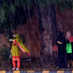 La gente espera para subir a un transporte público en una calle durante las fuertes lluvias en Karachi, Pakistán. | Foto:Asif Hassan / AFP