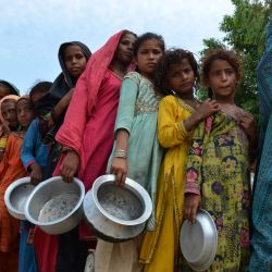 Los desplazados por las inundaciones hacen cola para recibir alimentos distribuidos por Saylani Welfare Trust en un campamento improvisado en Sehwan, provincia de Sindh, afectada por las inundaciones. | Foto:Husnain Ali / AFP