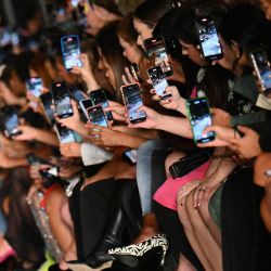 Los invitados sostienen sus teléfonos celulares para grabar el show de Boohoo by Kourtney Kardashian durante la Semana de la Moda de Nueva York en la ciudad de Nueva York. | Foto:ANGELA WEISS / AFP