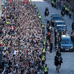 Miembros del público observan la procesión del féretro de la difunta Reina Isabel II, desde el Palacio de Holyroodhouse hasta la Catedral de St Giles en Edimburgo, en la Milla Real, donde la Reina Isabel II descansará. | Foto:Oli Scarff / AFP