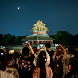 La gente toma fotos de la luna y de una torre histórica cerca de la Ciudad Prohibida durante el festival de mediados de otoño en Beijing. | Foto:Jade Gao / AFP