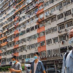 Los peatones cruzan una carretera junto a los bloques de apartamentos en la zona de To Kwa Wan de Hong Kong. | Foto:Bertha Wang / AFP