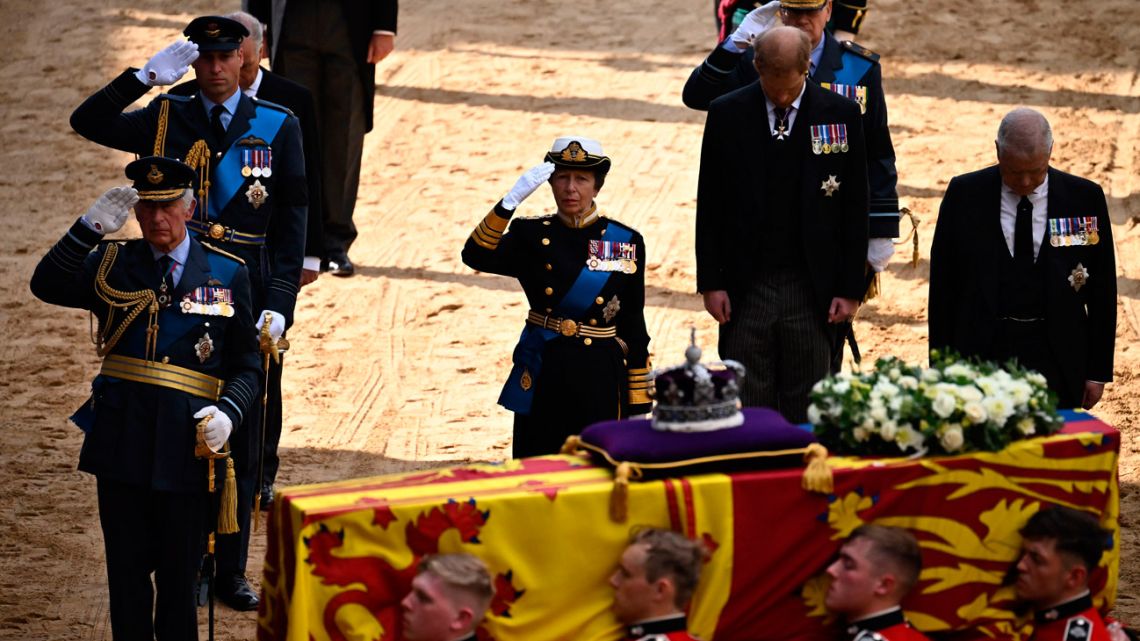 Britain's King Charles III, Britain's Prince William, Prince of Wales and Britain's Princess Anne, Princess Royal salute, alongside Britain's Prince William, Prince of Wales and Britain's Prince Andrew, Duke of York as the coffin of Queen Elizabeth II, adorned with a Royal Standard and the Imperial State Crown, arrives at the Palace of Westminster, following a procession from Buckingham Palace, in London on September 14, 2022.