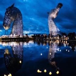 Las estatuas de Kelpies, diseñadas por el artista escocés Andy Scott, se iluminan mientras los miembros del público celebran un servicio de reflexión para mostrar su respeto a la difunta reina Isabel II, en Falkirk, Escocia. | Foto:Andy Buchanan / AFP