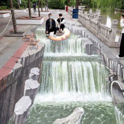 Esta foto muestra a personas tomándose fotos con una pintura callejera en 3D en Handan, en la provincia septentrional china de Hebei. | Foto:AFP