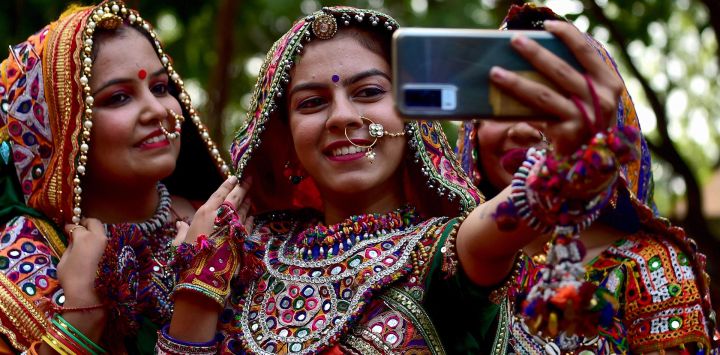 Participantes de un grupo artístico con vestidos tradicionales posan para un selfie durante los ensayos de danza Garba antes del festival Navratri en Ahmedabad, India.