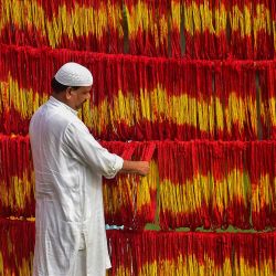 El propietario de un taller comprueba los "hilos Kalawa" recién teñidos, un hilo sagrado tradicional de color amarillo anaranjado que se utiliza en los rituales hindúes, antes del festival Navratri en la aldea de Lalgopalganj, a unos 45 kilómetros de Allahabad, India. | Foto:SANJAY KANOJIA / AFP