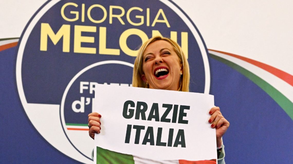 Leader of Italian far-right party 'Fratelli d'Italia' (Brothers of Italy), Giorgia Meloni reacts as she holds a placard reading 'Thank You Italy' after she delivered an address at her party's campaign headquarters overnight on September 26, 2022 in Rome, after the country voted in a legislative election.