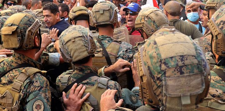 Soldados del ejército libanés se enfrentan a militares retirados mientras intentan irrumpir en el parlamento en Beirut, durante una sesión para aprobar el presupuesto de 2022.