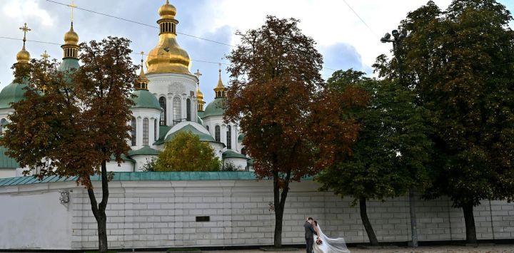 Una pareja de recién casados se besa en el centro de Kiev, justo después de su boda.