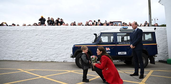 El Príncipe de Gales, Guillermo, observa cómo su esposa, la Princesa de Gales, Catalina, recibe un ramo de flores de Theo Crompton, de cuatro años, durante su visita a la estación de botes salvavidas de Holyhead del RNLI (Royal National Lifeboat Institution) en Anglesey, al noroeste de Gales.