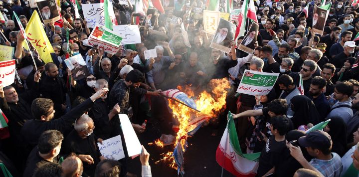 Manifestantes progubernamentales iraníes queman banderas de Estados Unidos, Israel y Gran Bretaña durante una manifestación contra las recientes protestas antigubernamentales en Irán, en Teherán.