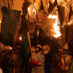 Participantes con gorro y guantes para protegerse de las quemaduras llevan antorchas hechas con odres en llamas, durante la procesión de antorchas de "El Vitor", en Mayorga, España. | Foto:CESAR MANSO / AFP