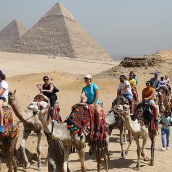 Turistas montan camellos mientras visitan el punto escénico de las Pirámides de Giza durante el Día Mundial del Turismo, en Giza, Egipto. Egipto abrió la mayoría de sus museos y sitios arqueológicos, incluyendo las Pirámides de Giza, a los visitantes de manera gratuita con motivo del Día Mundial del Turismo. | Foto:Xinhua/Ahmed Gomaa