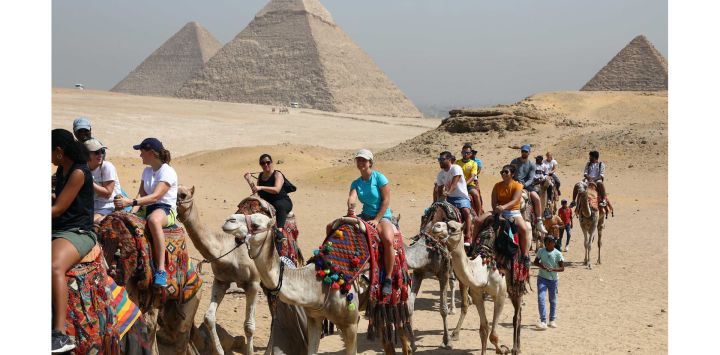 Turistas montan camellos mientras visitan el punto escénico de las Pirámides de Giza durante el Día Mundial del Turismo, en Giza, Egipto. Egipto abrió la mayoría de sus museos y sitios arqueológicos, incluyendo las Pirámides de Giza, a los visitantes de manera gratuita con motivo del Día Mundial del Turismo.