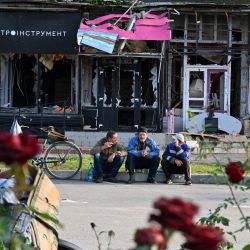Los residentes locales se sientan frente a las tiendas dañadas en Izyum, región de Kharkiv, en medio de la invasión rusa en Ucrania. | Foto:SERGEY BOBOK / AFP