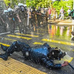 Un miembro del personal de seguridad cae mientras la policía utiliza cañones de agua para dispersar a los manifestantes antigubernamentales durante una manifestación en Colombo, Sri Lanka. | Foto:ISHARA S. KODIKARA / AFP