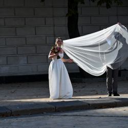 Un novio endereza el velo de novia en el centro de la capital ucraniana de Kiev, justo después de su boda. | Foto:SERGEI SUPINSKY / AFP