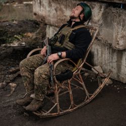Un soldado ucraniano posa en una mecedora en un puesto de control en la región de Kharkiv. | Foto:YASUYOSHI CHIBA / AFP