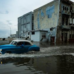 Un viejo coche americano pasa por una calle inundada en La Habana, tras el paso del huracán Ian. | Foto:YAMIL LAGE / AFP