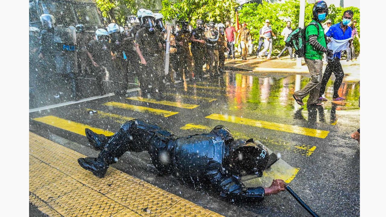 Un miembro del personal de seguridad cae mientras la policía utiliza cañones de agua para dispersar a los manifestantes antigubernamentales durante una manifestación en Colombo, Sri Lanka. | Foto:ISHARA S. KODIKARA / AFP