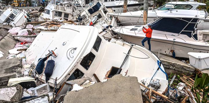 Un hombre toma fotos de los barcos dañados por el huracán Ian en Fort Myers, Florida.